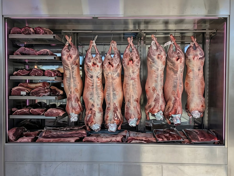 Whole lambs hanging in the cabinet at Ikhlas Halal Butcher, Bradford