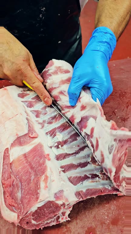 A butcher trimming a rack of lamb